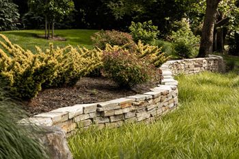 Stone retaining wall with landscaping and mulch beds